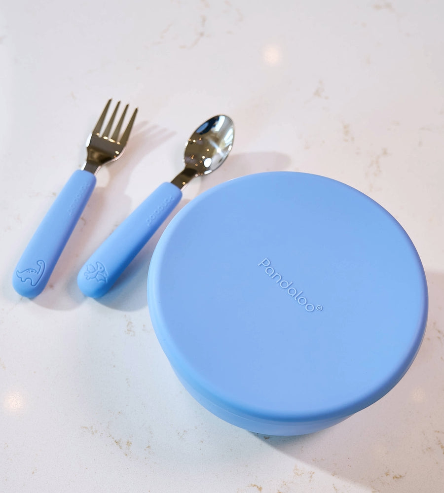 Pandaloo Kids stainless steel fork and spoon with blue silicone handles next to a blue porcelain bowl with a silicone lid